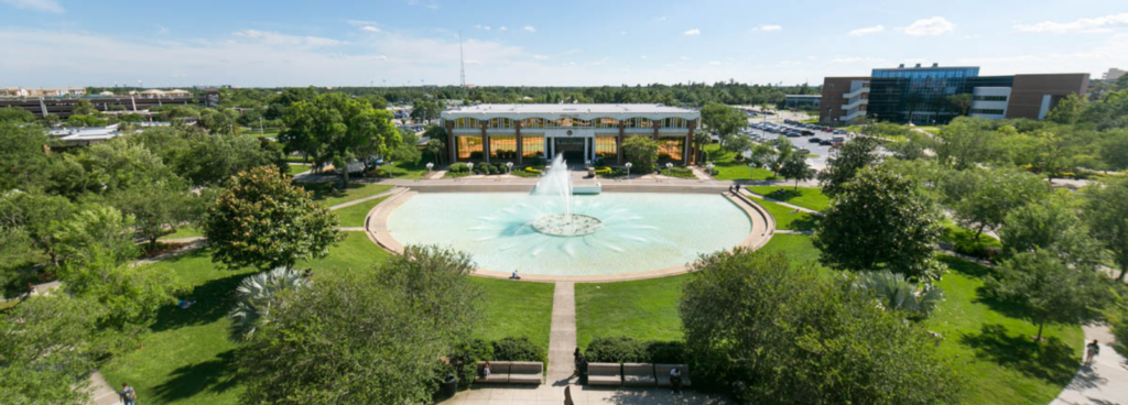 University of Central Florida main campus in Orlando aerial view looking at the administration building, Millican Hall, and the reflecting pond on a sunny day with blue skies