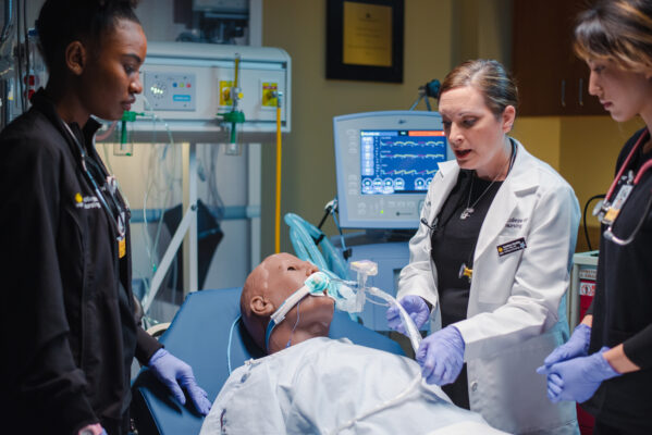 Professor and students using high-tech healthcare manikin