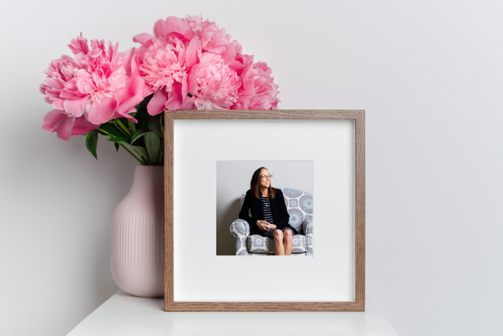 Photo frame of Joyce DeGennaro in front of a vase of pink flowers