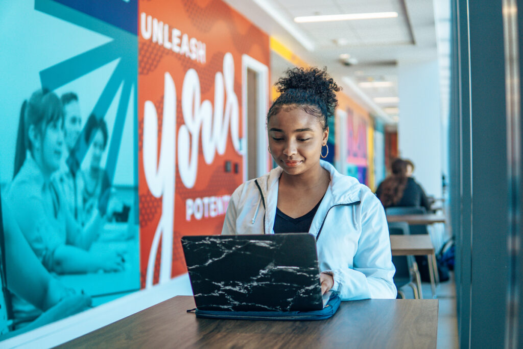 UCF student sits at a desk with a laptop