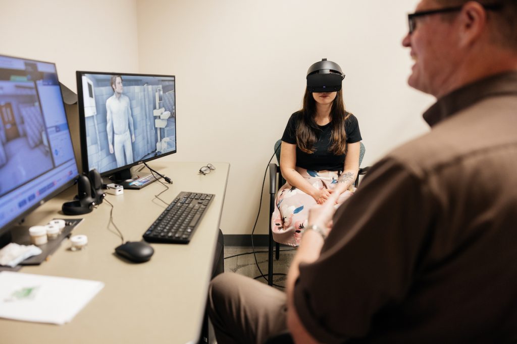 Patient wearing VR goggles receives a simulated therapy session with a UCF RESTORES team member to overcome PTSD.