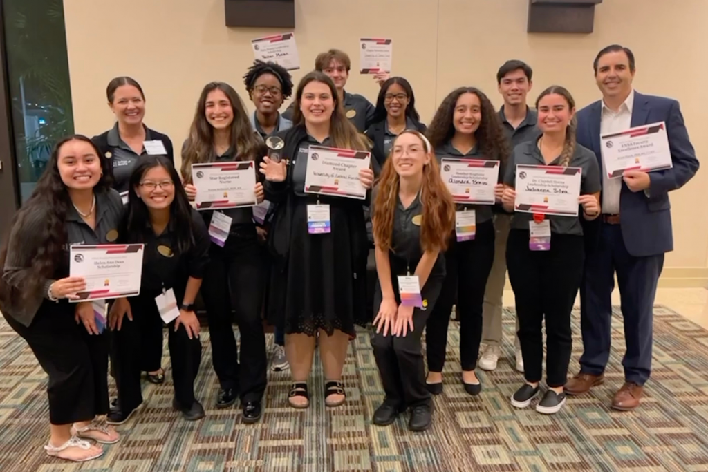 Student Nurses' Association at UCF Orlando board members and faculty advisors holding awards in a hotel lobby at the Florida Nursing Students Association 2023 Convention