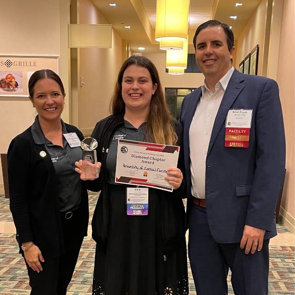 SNA at UCF Orlando president Jamielyn Lanza holds the FNSA 2023 Diamond Chapter Award, standing next to faculty advisors Kate Dorminy and Brian Peach