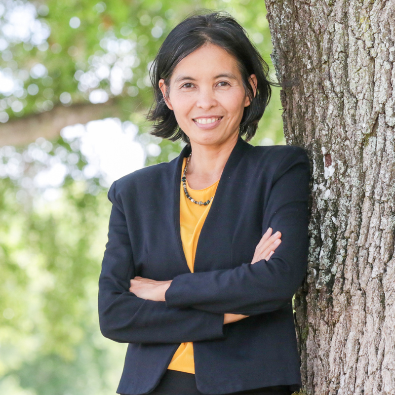 Ladda Thiamwong, a faculty member at UCF's College of Nursing, smiles and leans against a tree outside on the campus in Orlando, FL