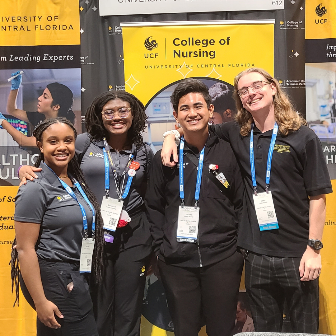 Four students wearing UCF College of Nursing polos and convention badges stand