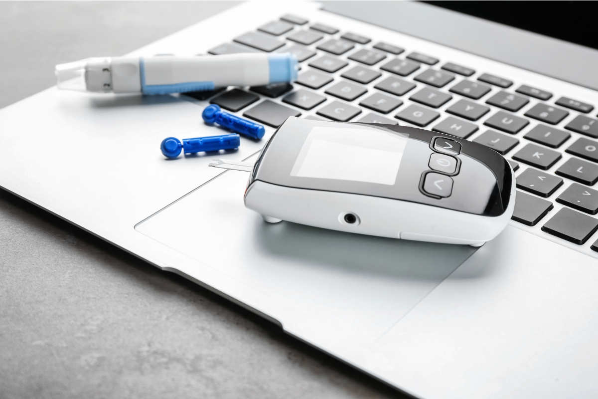 Laptop keyboard with diabetes monitoring equipment sitting on top.