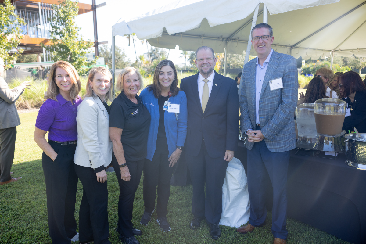 A group of leaders from AdventHealth stand outside in front of a tent with UCF President Alexander Cartwright and UCF College of Nursing Dean Mary Lou Sole