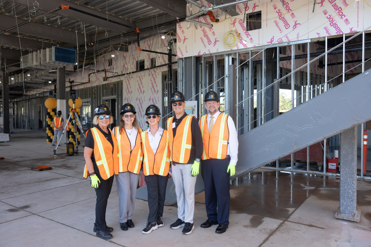 UCF President Alexander Cartwright and UCF College of Nursing Dean Mary Lou Sole stand in construction vests, gloves and hard hats with donors inside the Dr. Phillips Nursing Pavilion that is under construction