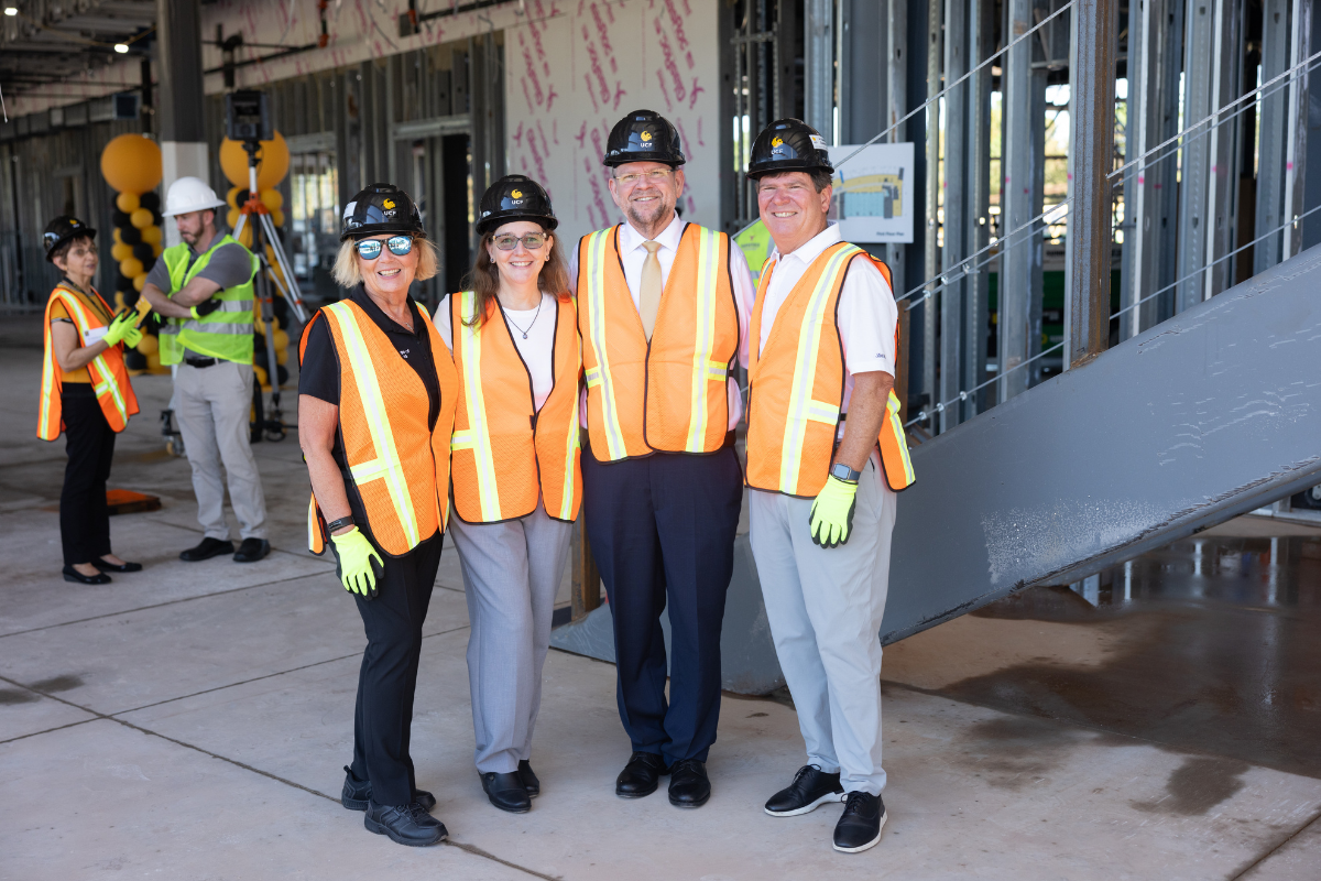 UCF President Alexander Cartwright and UCF College of Nursing Dean Mary Lou Sole stand in construction vests, gloves and hard hats with Ken Robinson from Dr. Phillips Charities inside the Dr. Phillips Nursing Pavilion that is under construction