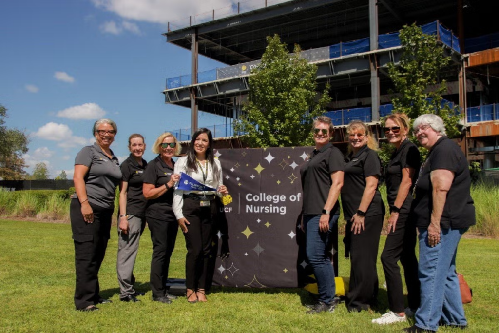 Angela Requena stands with Dean Mary Lou Sole and other nursing leaders in front of the Dr. Phillips Nursing Pavilion construction site.