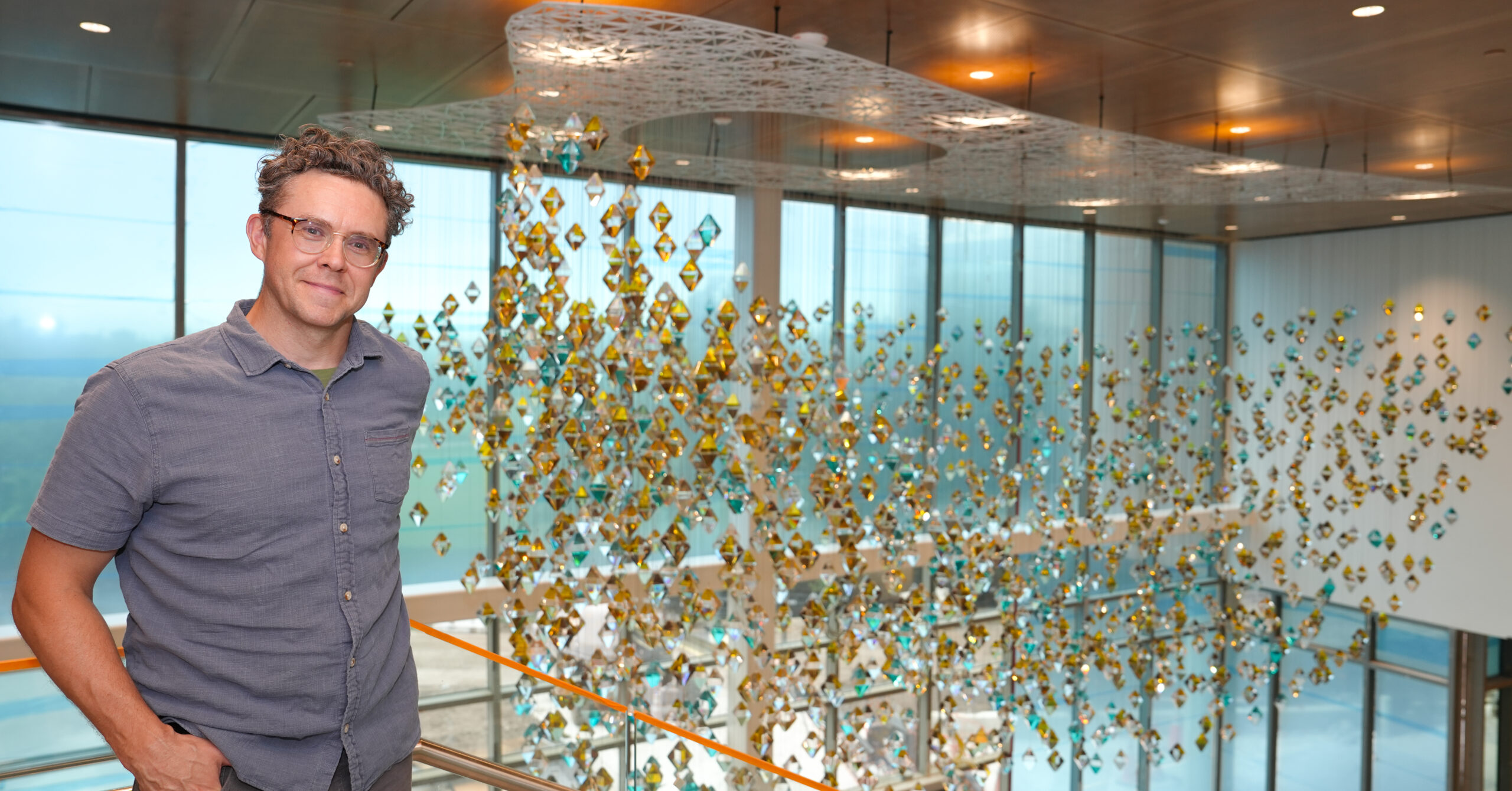 Brian W Brush smiling in front of his art at the Dr. Phillips Nursing Pavilion.