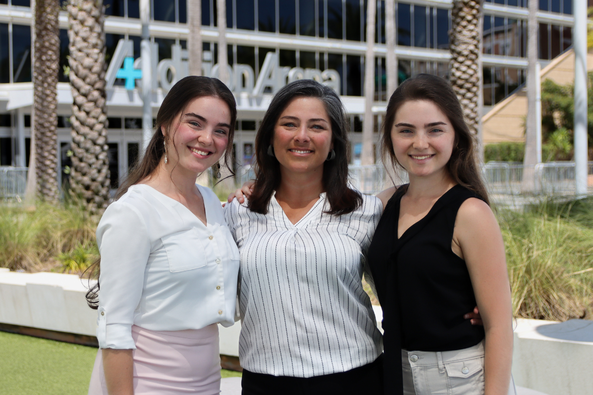 Twins Elizabeth and Hannah Scarborough stand on each side of their mom, Stacie, in front of Addition Financial Arena.