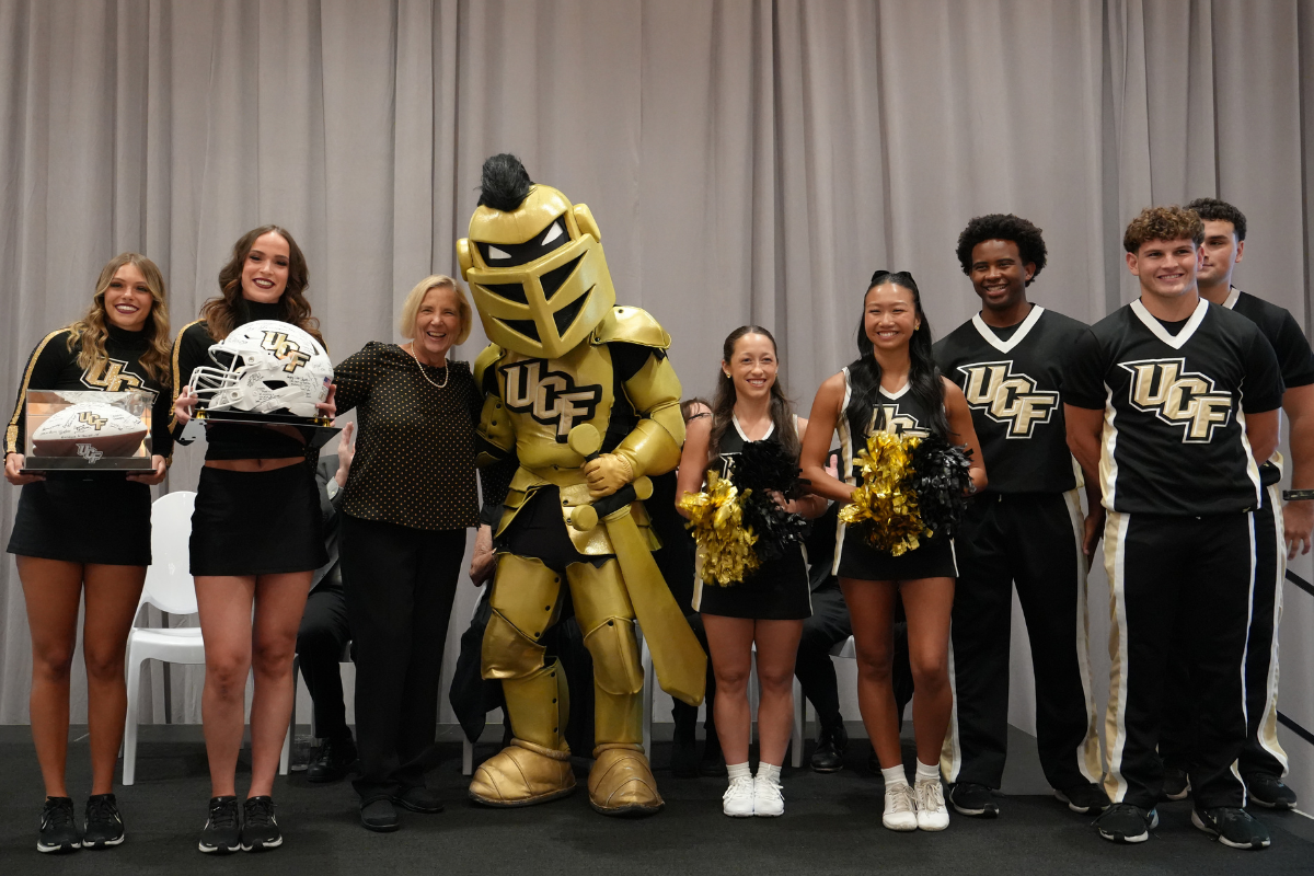 Dean Sole, Knightro and UCF cheer and dance team members smile on stage during an event.