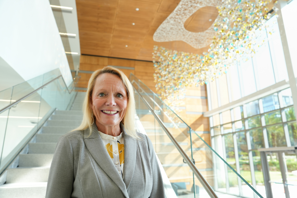 Dean Sharon Tucker smiles in front of the lobby stairway at the Dr. Phillips Nursing Pavilion.