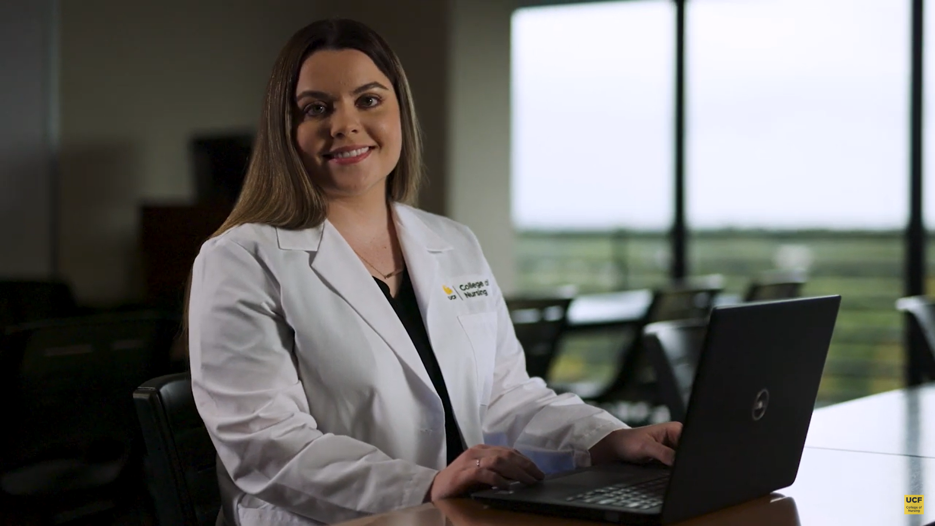 A student smiling with a laptop opened.
