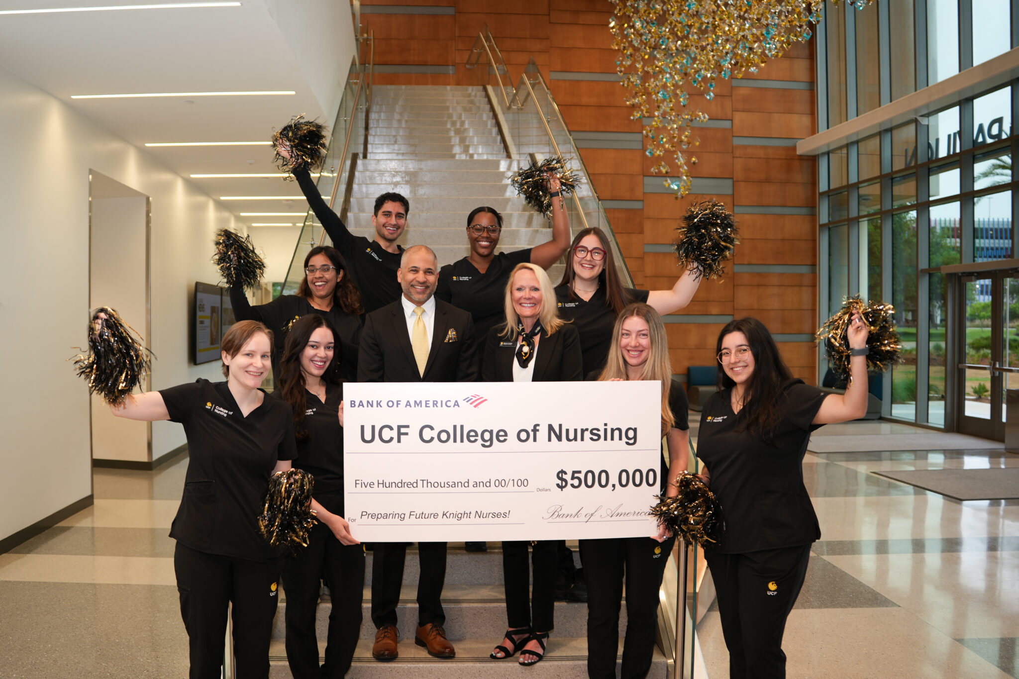 Dean Sharon Tucker and Bank of America President Naveed Shujaat holding a check of $500,000 surrounded by nursing students in pom poms.