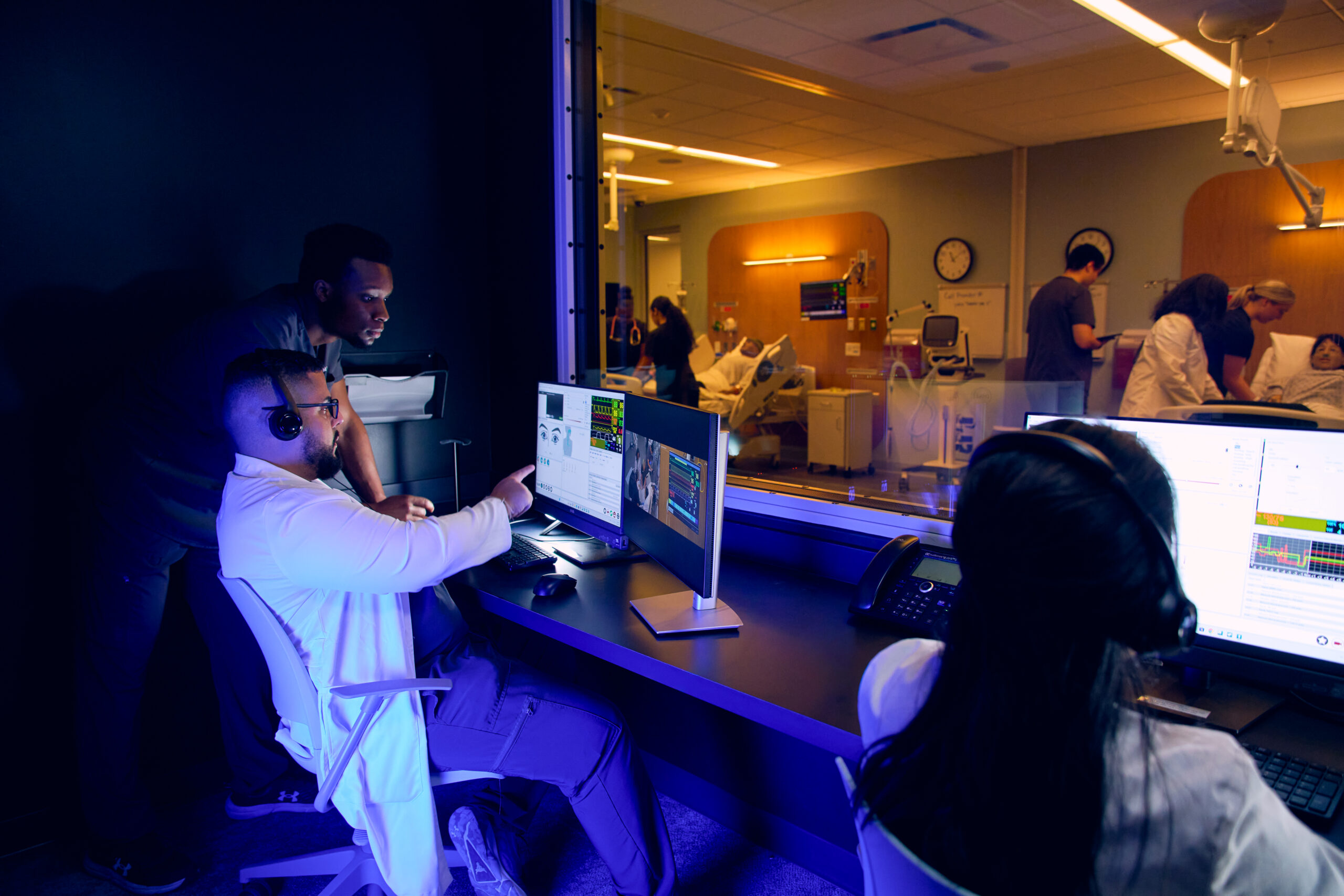 An instructor showing a simulation specialist something in a control room.